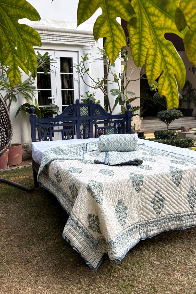 Handcrafted quilt featuring delicate blue floral prints and striped border finish