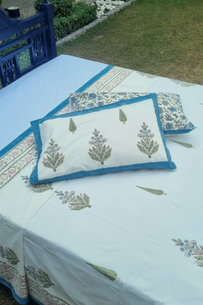 Premium white cotton bedsheet featuring hand block botanical print with blue border and matching pillow covers