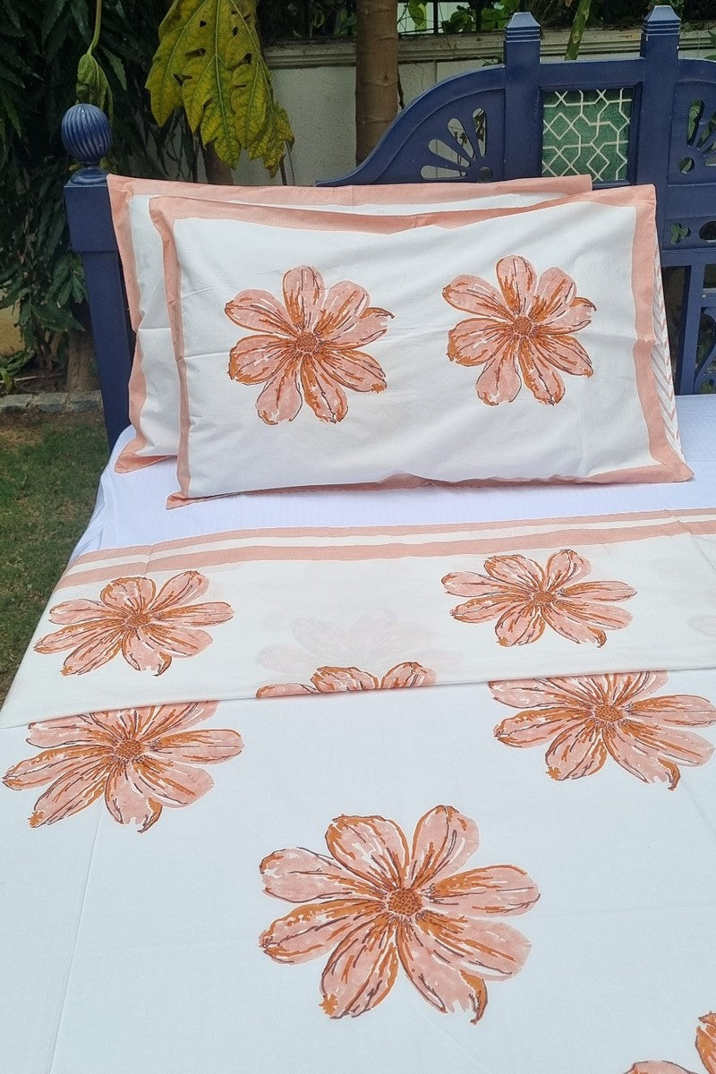 Peach blossom print cotton bedsheet set with coordinated pillow covers and striped hem border