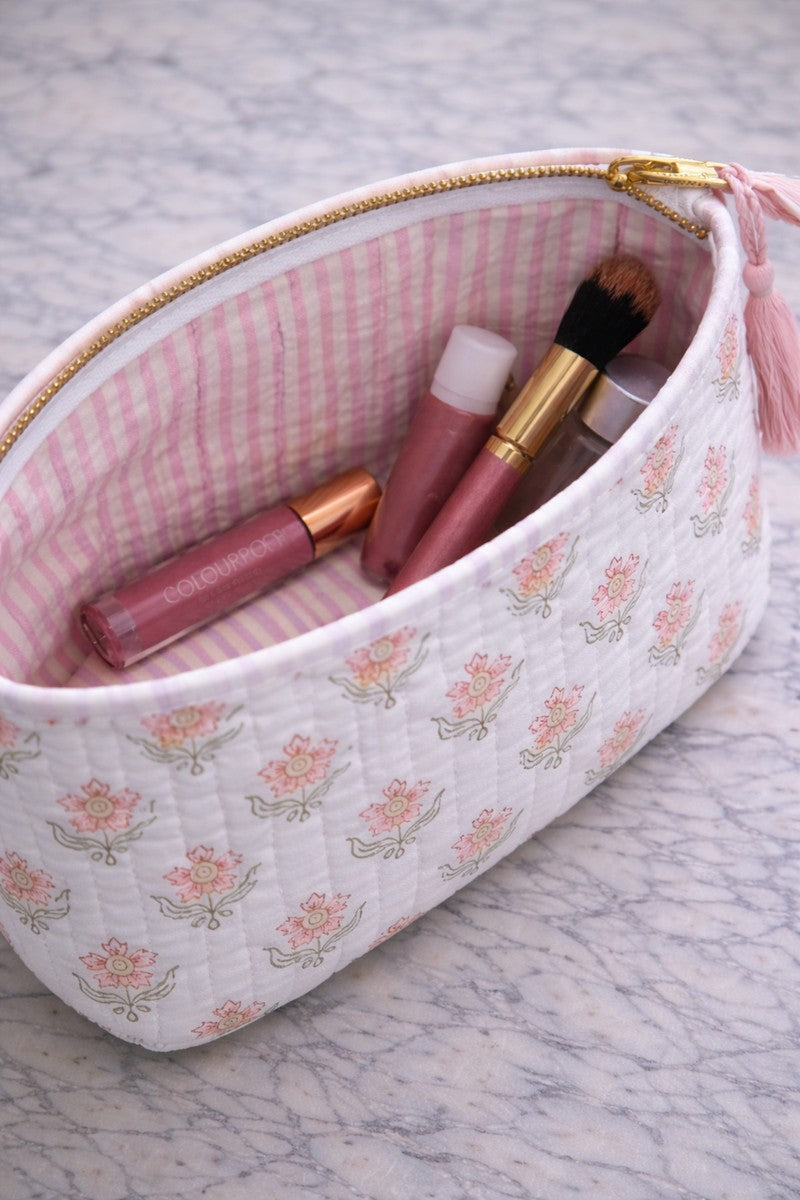 Close-up of blush handblock print cosmetic pouch with pink striped lining, gold zipper and tassel detail, quilted cotton makeup organizer.