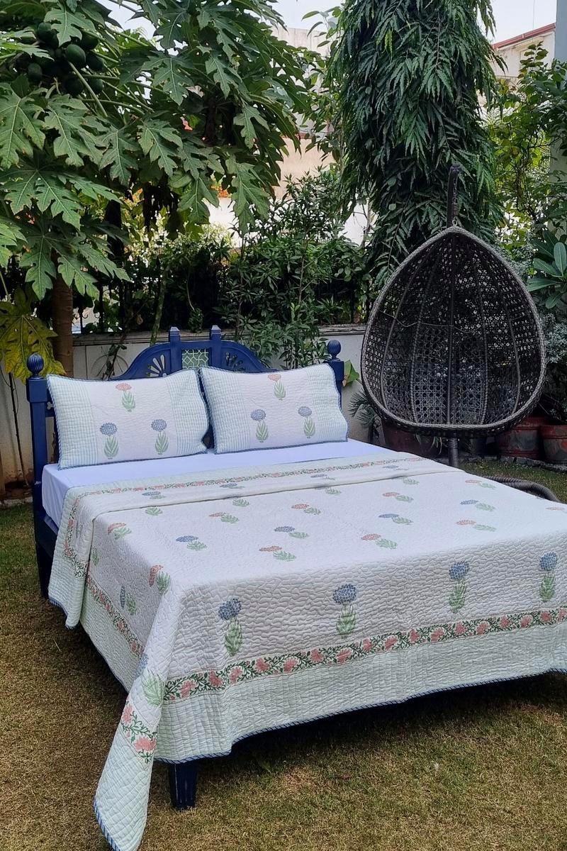 Hand block printed pastel floral cotton bedcover on soft white base with vine border