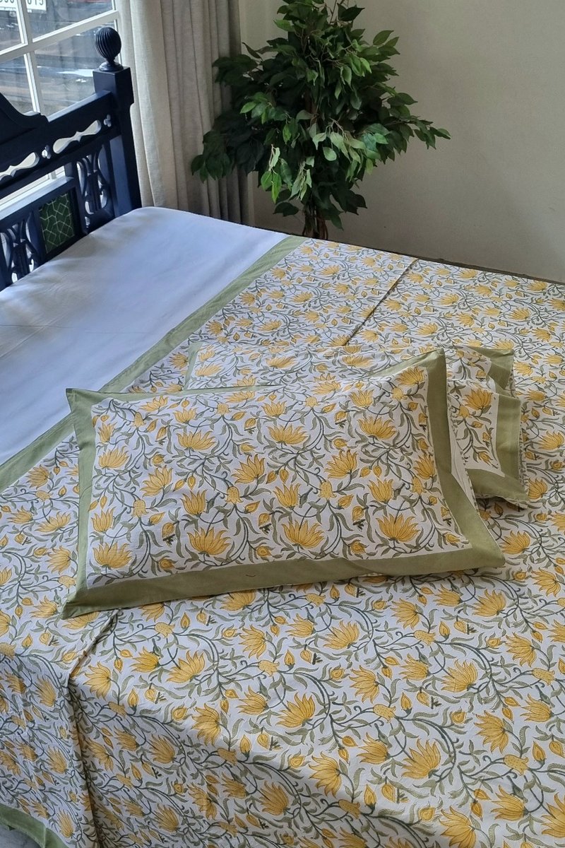 Yellow floral hand block print cotton bedsheet set with green border, king size bedding styled indoors