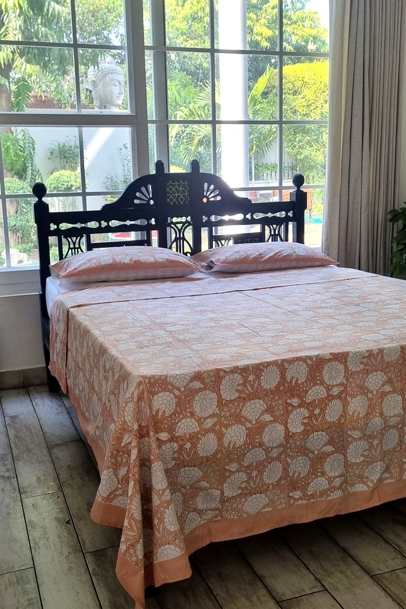 King size peach floral cotton bedsheet styled on wooden bed with natural light background