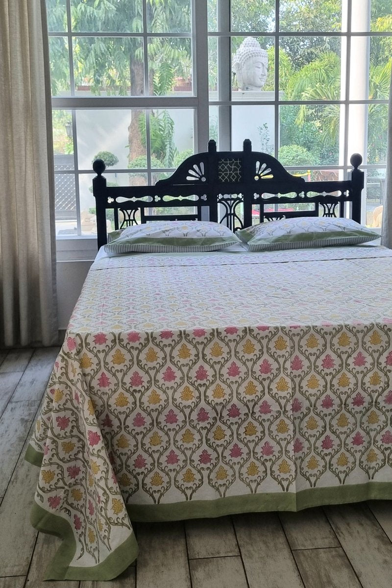 Close up of pink and yellow hand block printed cotton bedsheet with green edging
