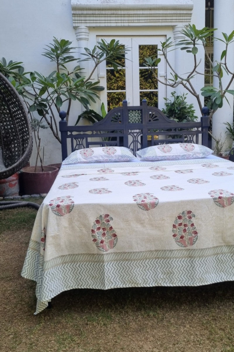 White cotton bedsheet with pink floral block print and sage chevron border on handcrafted wooden bed
