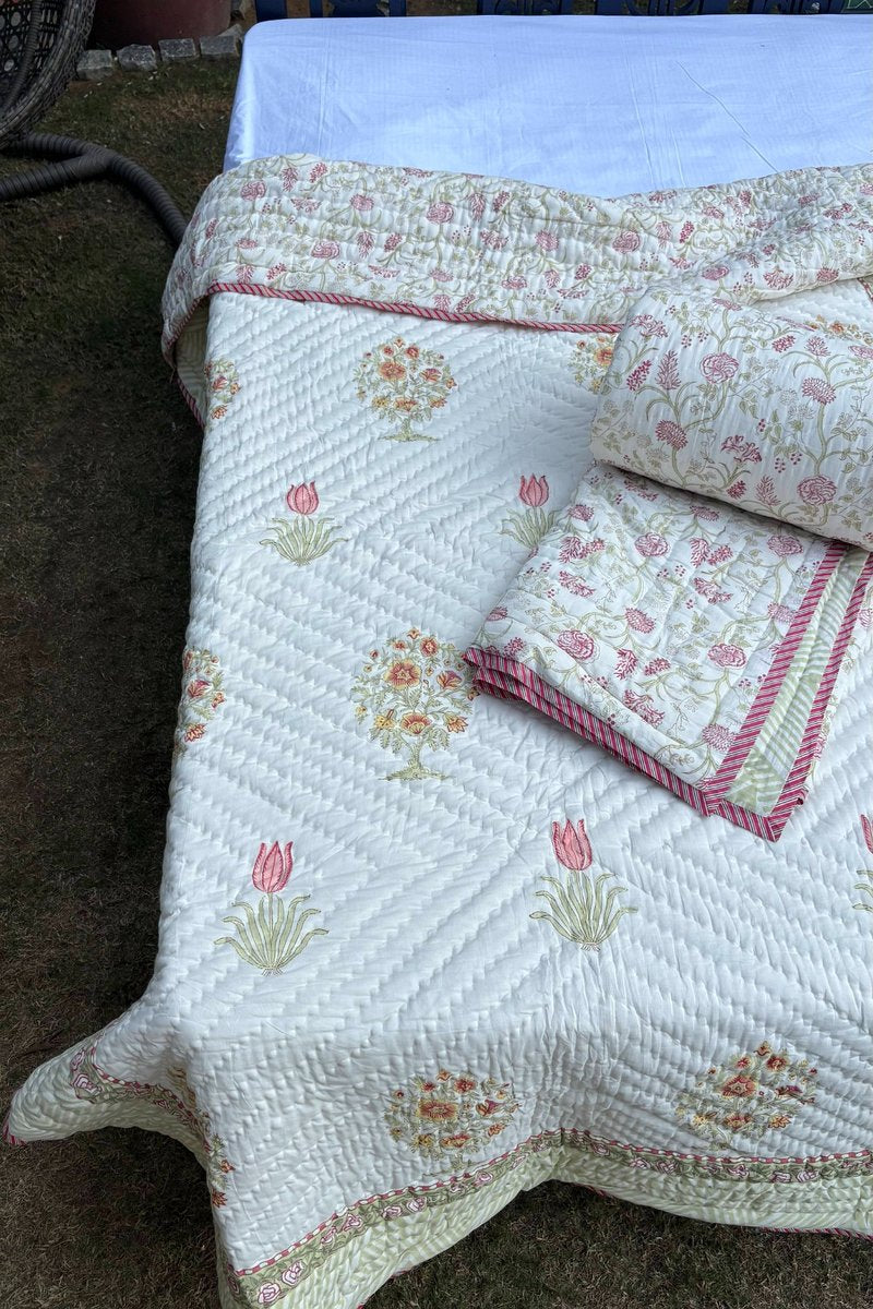 Close-up of cream hand block printed quilt featuring pink tulip motifs and floral border design