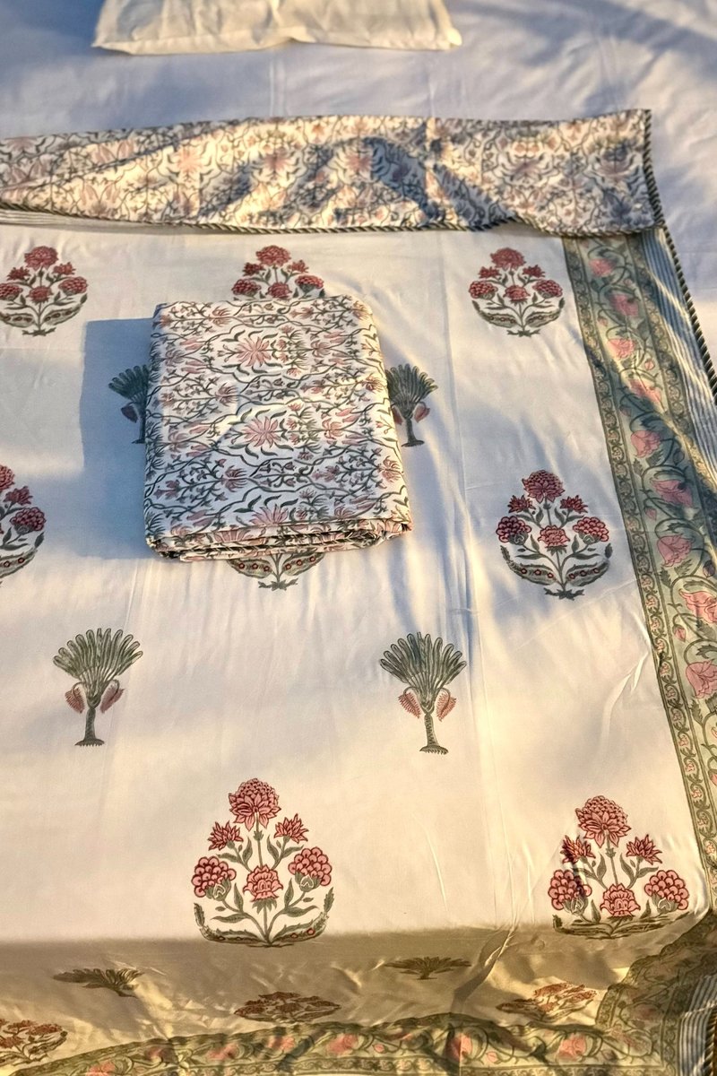 Premium hand block printed cotton dohar featuring pink bouquet motifs and olive palm trees with floral border, outdoor garden styling in natural daylight.