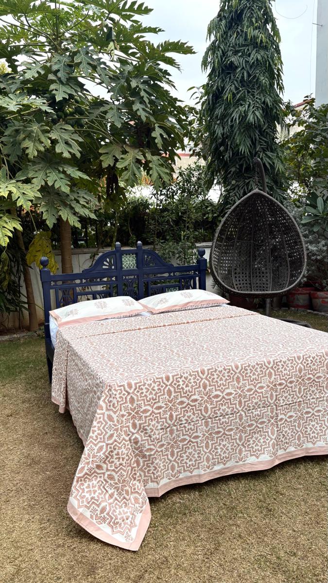 Morocco handblock print cotton bedsheet set styled outdoors with carved blue wooden bed and garden background