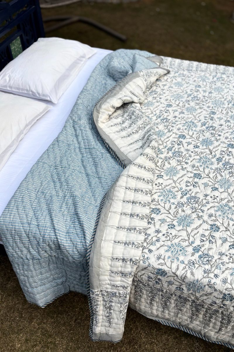 Blue and white hand block printed cotton quilt on full bed, traditional floral design with handcrafted Indian detailing