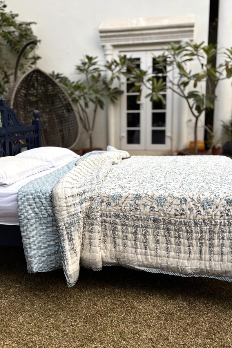 Close-up of blue hand block printed quilt showing floral pattern, quilted texture and soft cotton craftsmanship