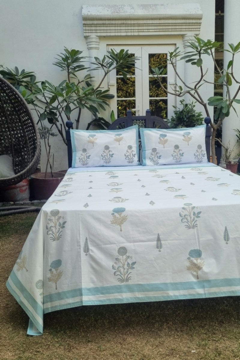 Jaipur block print double bedsheet set in aqua blue and beige floral pattern styled on wooden bed in garden
