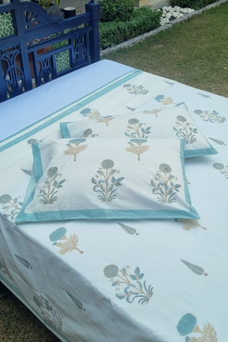 Elegant aqua blue floral block printed bedsheet styled outdoors with botanical garden backdrop
