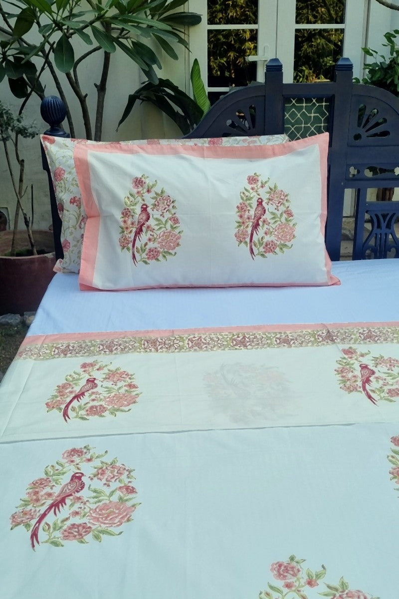 Hand block printed cotton bedsheet with pink floral bird motif, premium king size bed linen in garden backdrop