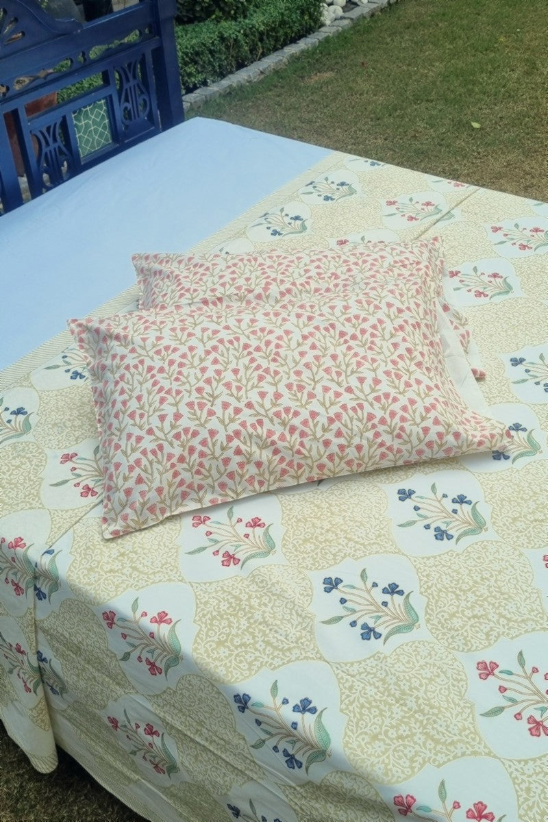 Close-up of hand block print cotton bedsheet featuring beige trellis pattern with red and blue floral buti design