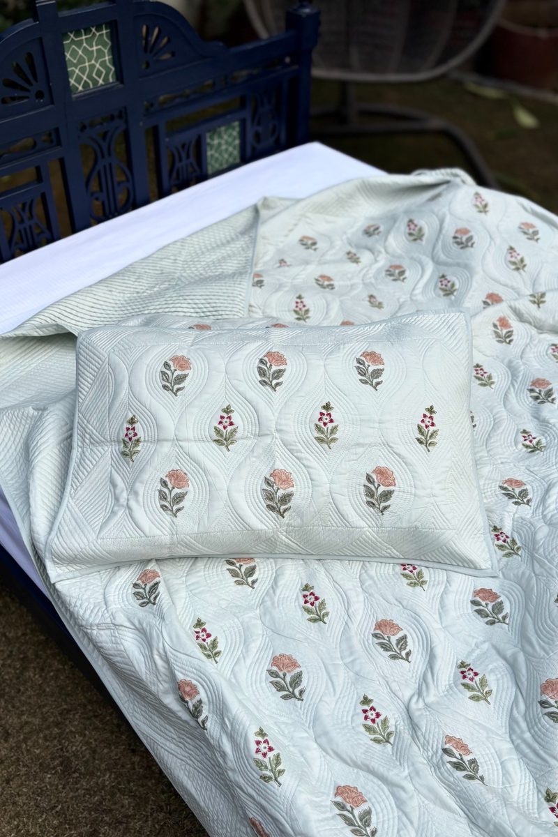 Handcrafted white cotton quilt with floral block print, luxury artisan bedding styled outdoors