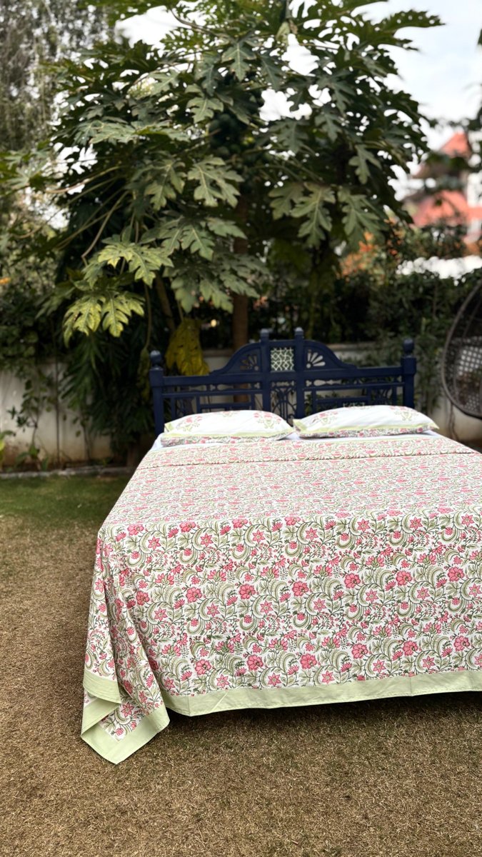 Close up of rose jaal handblock print showing detailed pink flowers and green vine pattern on white cotton fabric