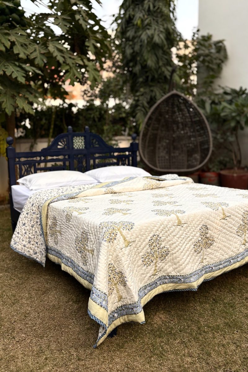 Handcrafted cream cotton quilt with blue tree block print, detailed border and natural quilted finish