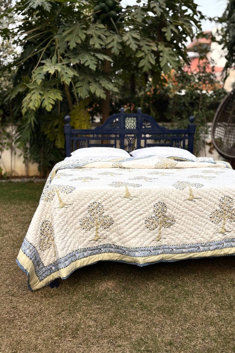 Artisan-made cream block print quilt featuring blue tree motifs, soft quilted cotton bedding