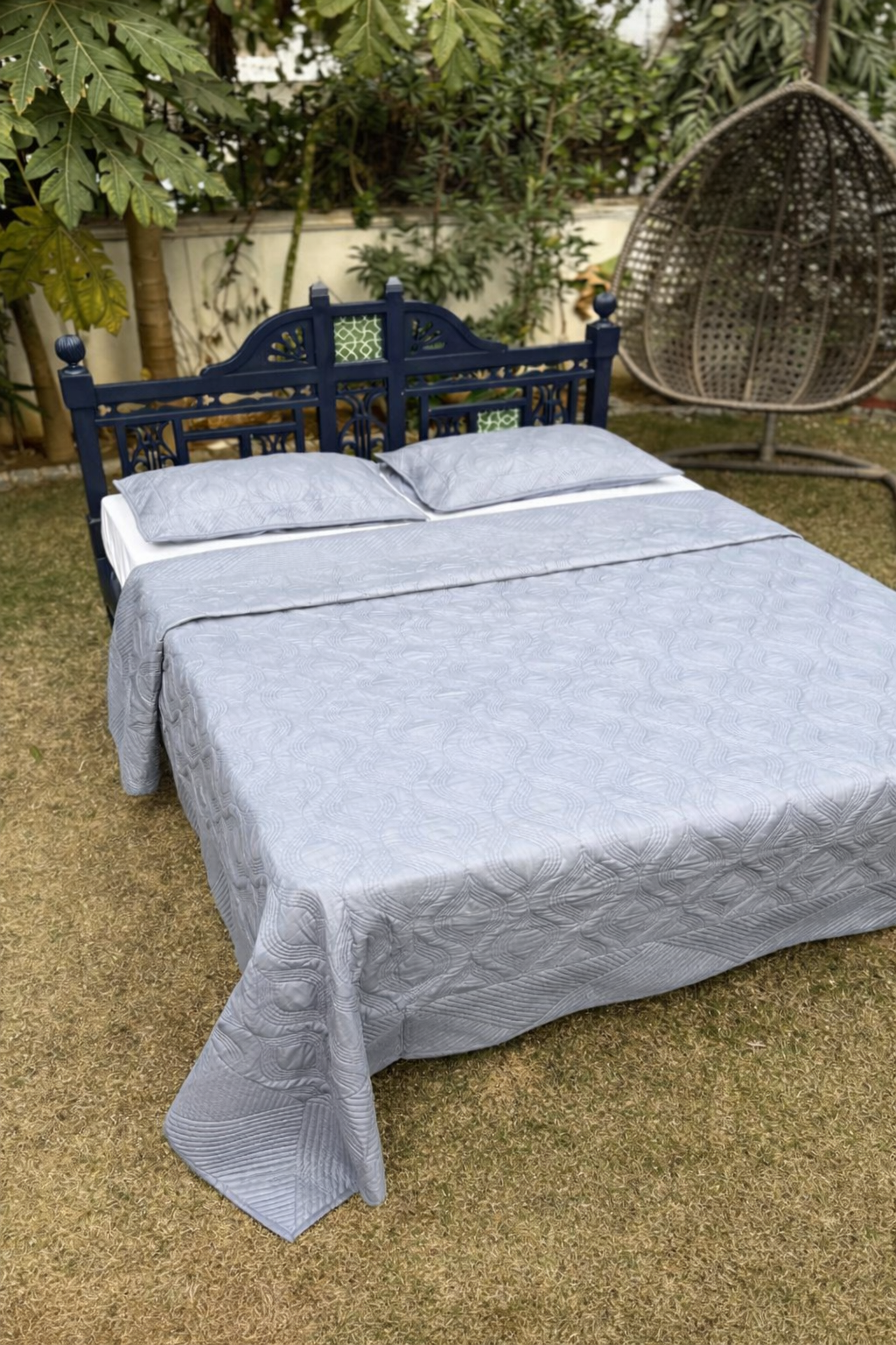 Luxury solid grey quilted bedspread with geometric pattern styled in serene garden bedroom