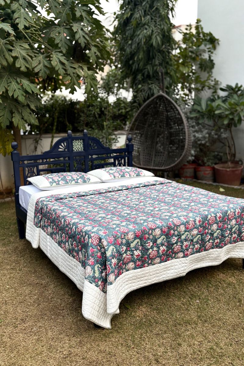 Floral hand block print quilt set with matching pillows in teal and rose tones, artisan cotton bedding