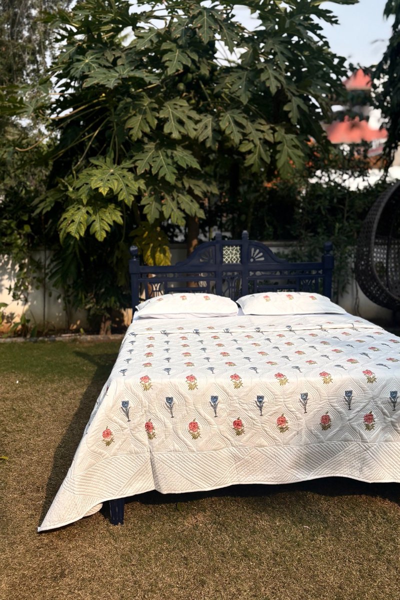 Luxury cream floral quilt set with hand quilting, Gulnaar Garden design displayed in natural garden setting