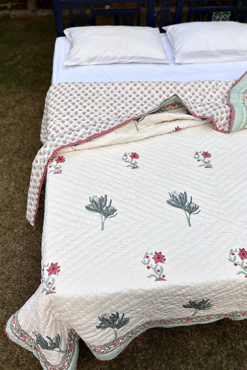 Hand block printed cotton quilt with delicate floral motifs and quilted texture, folded to show border detailing