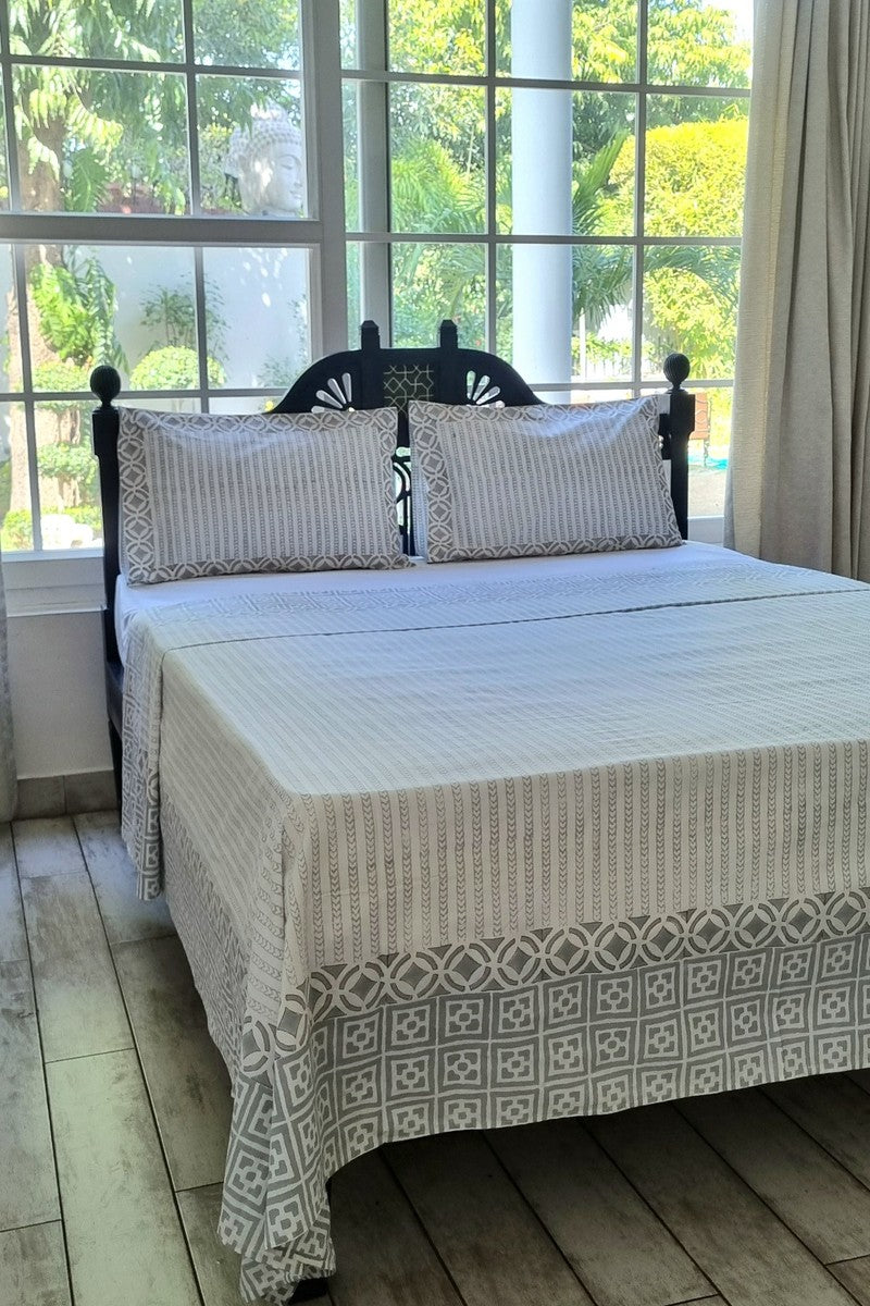 Minimalist grey block print cotton double bedsheet with matching pillow covers near large window