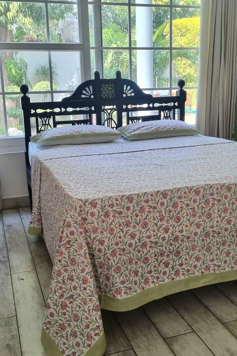 Close up of pink floral block print cotton bedsheet with matching pillow covers and green edging