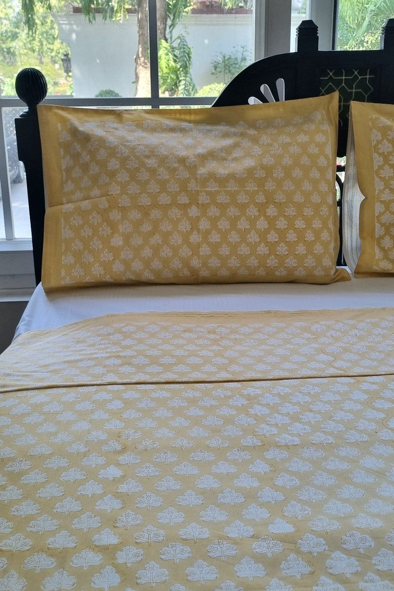 Close-up of yellow cotton bedsheet featuring white floral buta hand block print with matching pillow cover