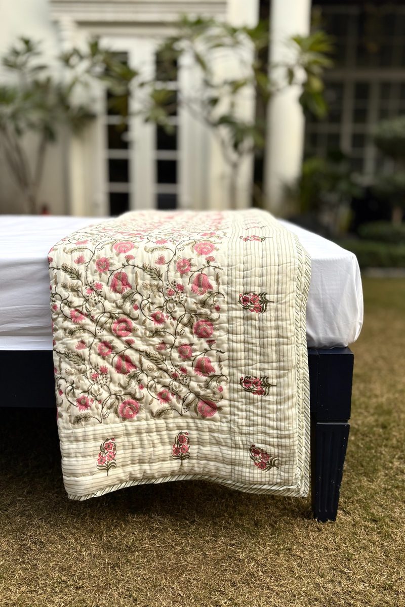 Hand block printed Jaal Bagh quilt with floral jaal pattern and striped border, styled folded on a bed