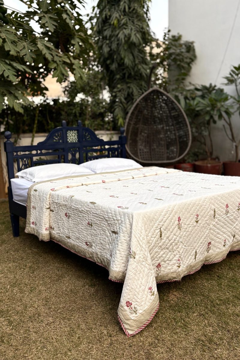 Cream hand block printed cotton quilt on full bed, minimal floral design with soft quilted texture
