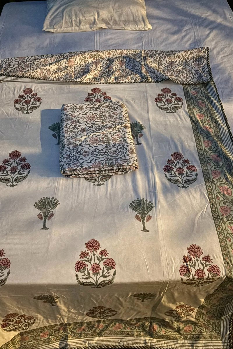 Close up of hand block print cotton dohar with pink floral buta and green palm tree design, matching printed pillow cover and detailed vine border.