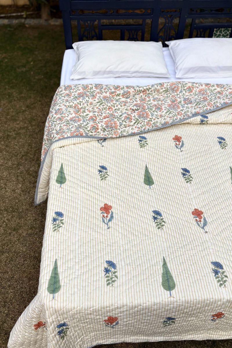 Reversible hand block printed quilt showing floral print and fine cotton stitching detail, close-up view