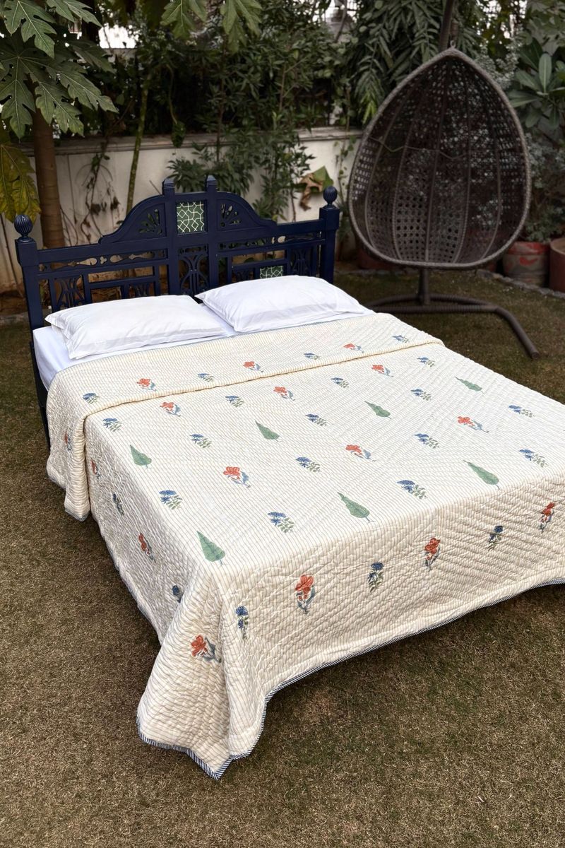 Traditional Indian hand block print quilt with small multicolor floral motifs, styled on a queen size bed