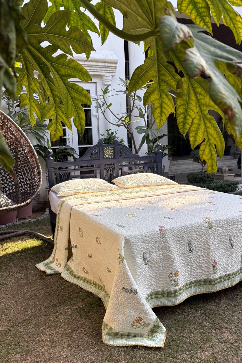 Hand block printed cotton quilted bedcover in soft ivory with delicate floral motifs and green border, luxury garden styled bedding set India