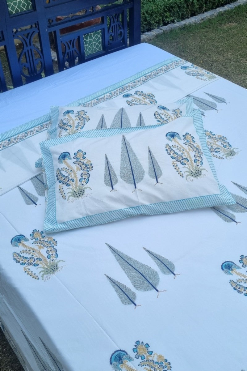 Luxury cotton double bedsheet with aqua floral design and striped border photographed in heritage garden backdrop