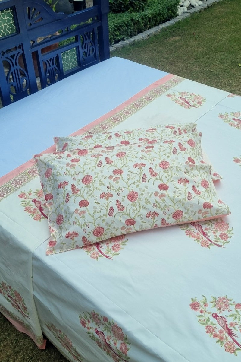 Close up of pink floral parrot motif hand block print cotton bedsheet with decorative border detail