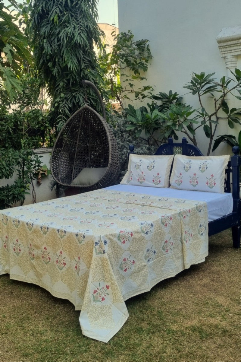 Jaipur hand block printed beige bedsheet set with floral motifs and matching pillow covers styled outdoors