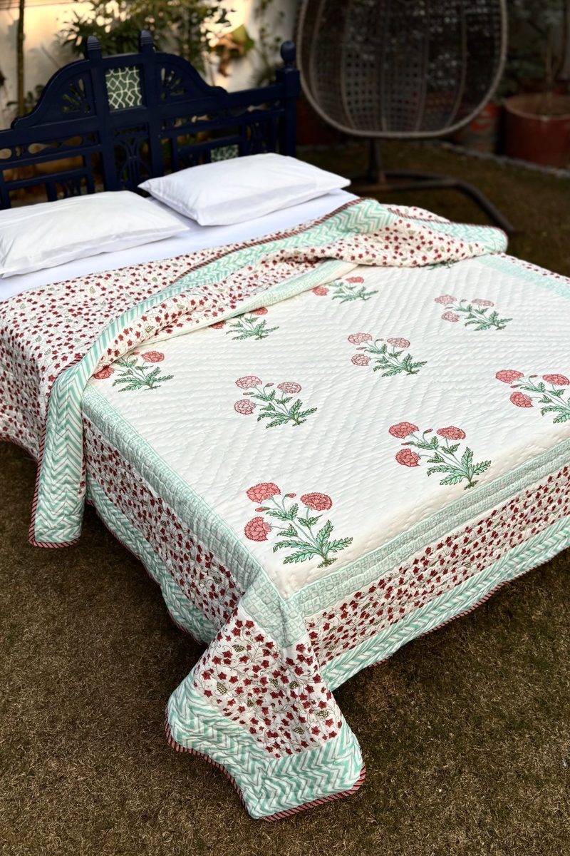 Close-up of hand block printed cotton quilt showing floral motifs, quilted texture and traditional Indian craftsmanship