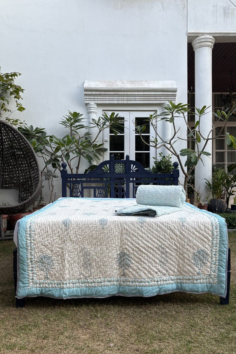 Close-up of hand block printed aqua palm and leopard quilt with detailed stitching and geometric border