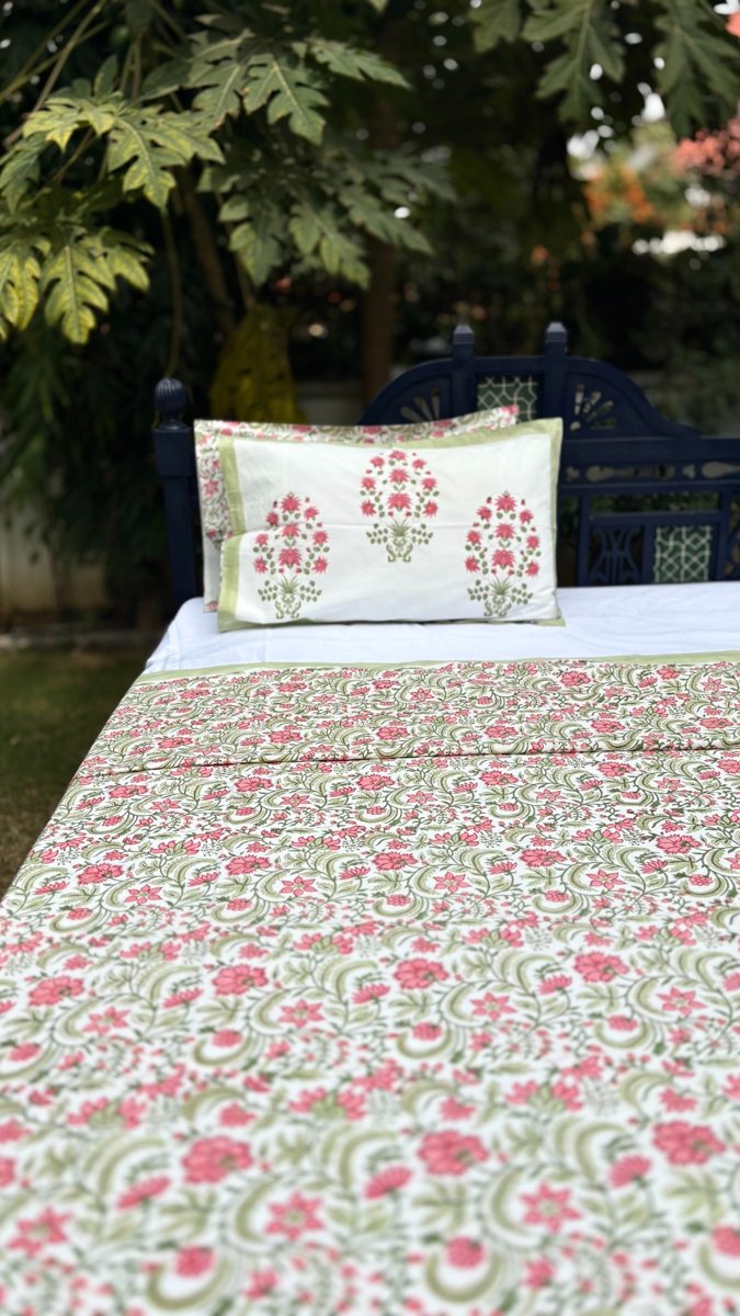 Rose jaal block print bedsheet set with coordinated pillow covers styled on blue carved wooden bed outdoors