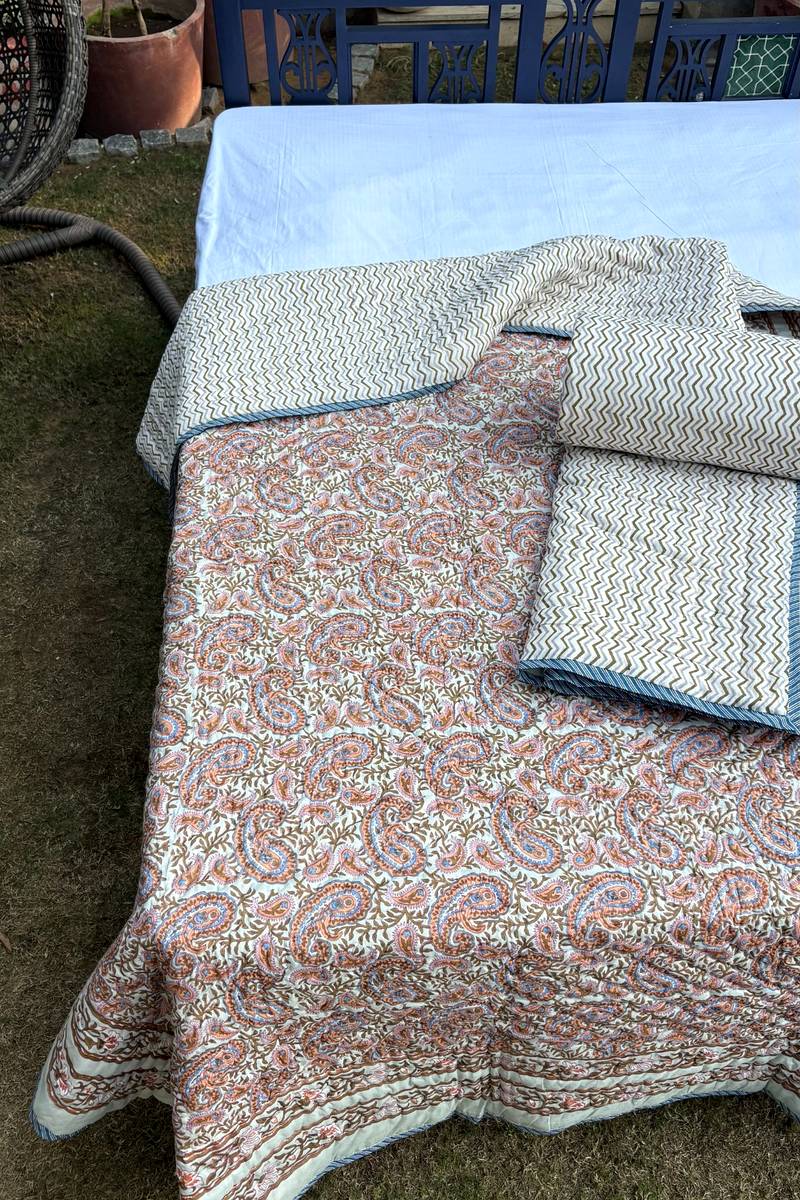 Heritage style paisley cotton quilt with detailed border print styled on classic blue wooden bed