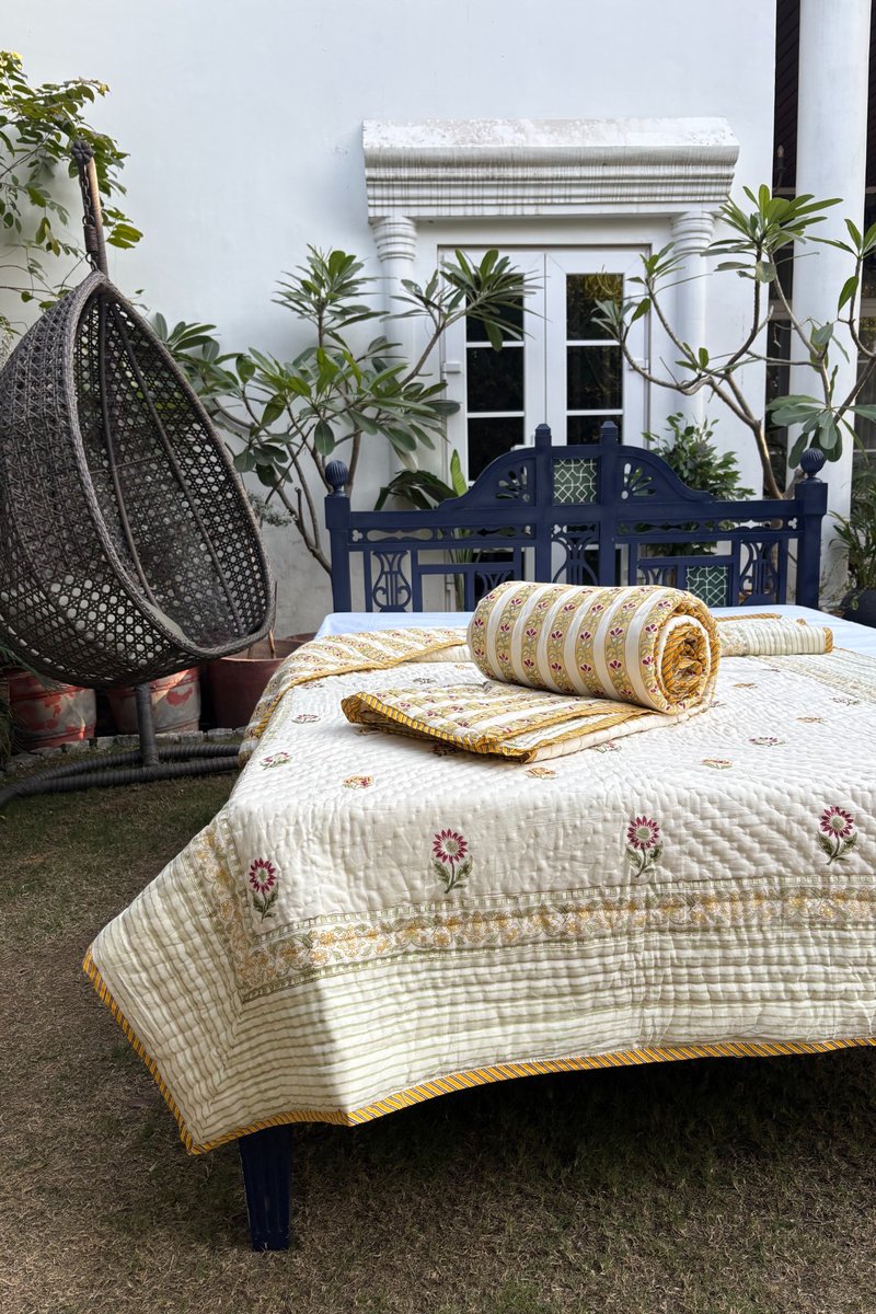 Close-up of ivory floral quilt set with mustard striped border 