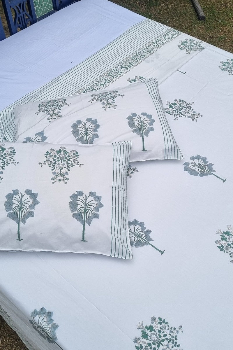 Close up of sage green tree motif handblock printed pillow covers and cotton bedsheet with detailed border design