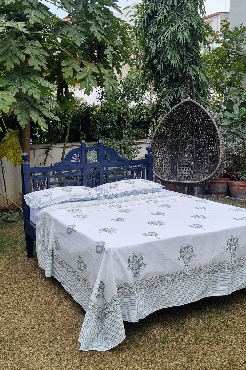 Floral block print cotton bedsheet with matching pillow covers displayed on double bed in garden setting