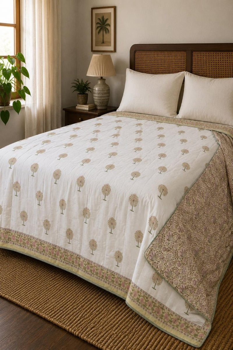 A white quilted dohar with a repeating beige tree pattern and a floral border, styled on a bed with matching white pillows in a warm, neutral-toned bedroom.