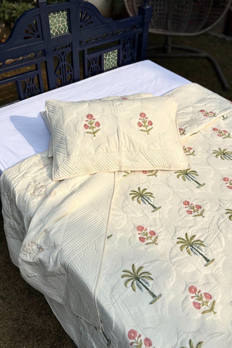 Hand quilted ivory cotton quilt featuring palm tree and floral motifs, detailed stitching
