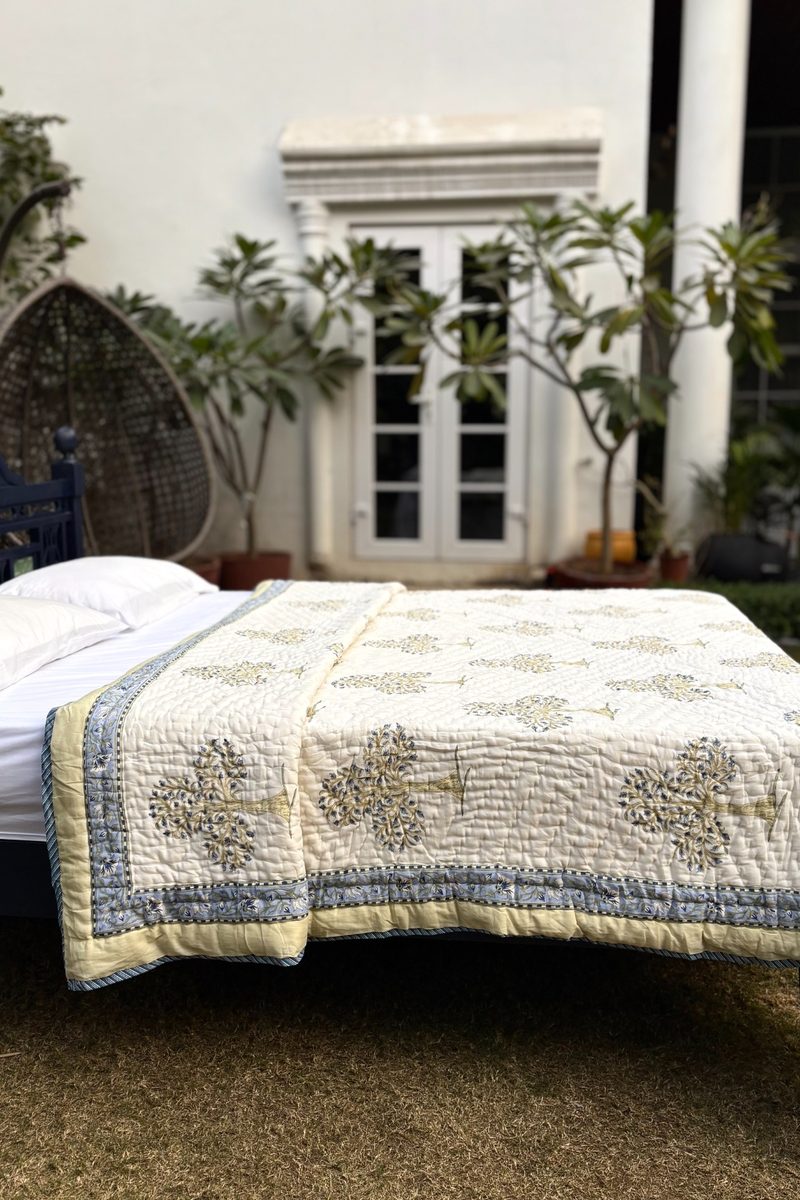 Hand block printed cream cotton quilt with blue tree motif, quilted texture and artisanal Indian craftsmanship